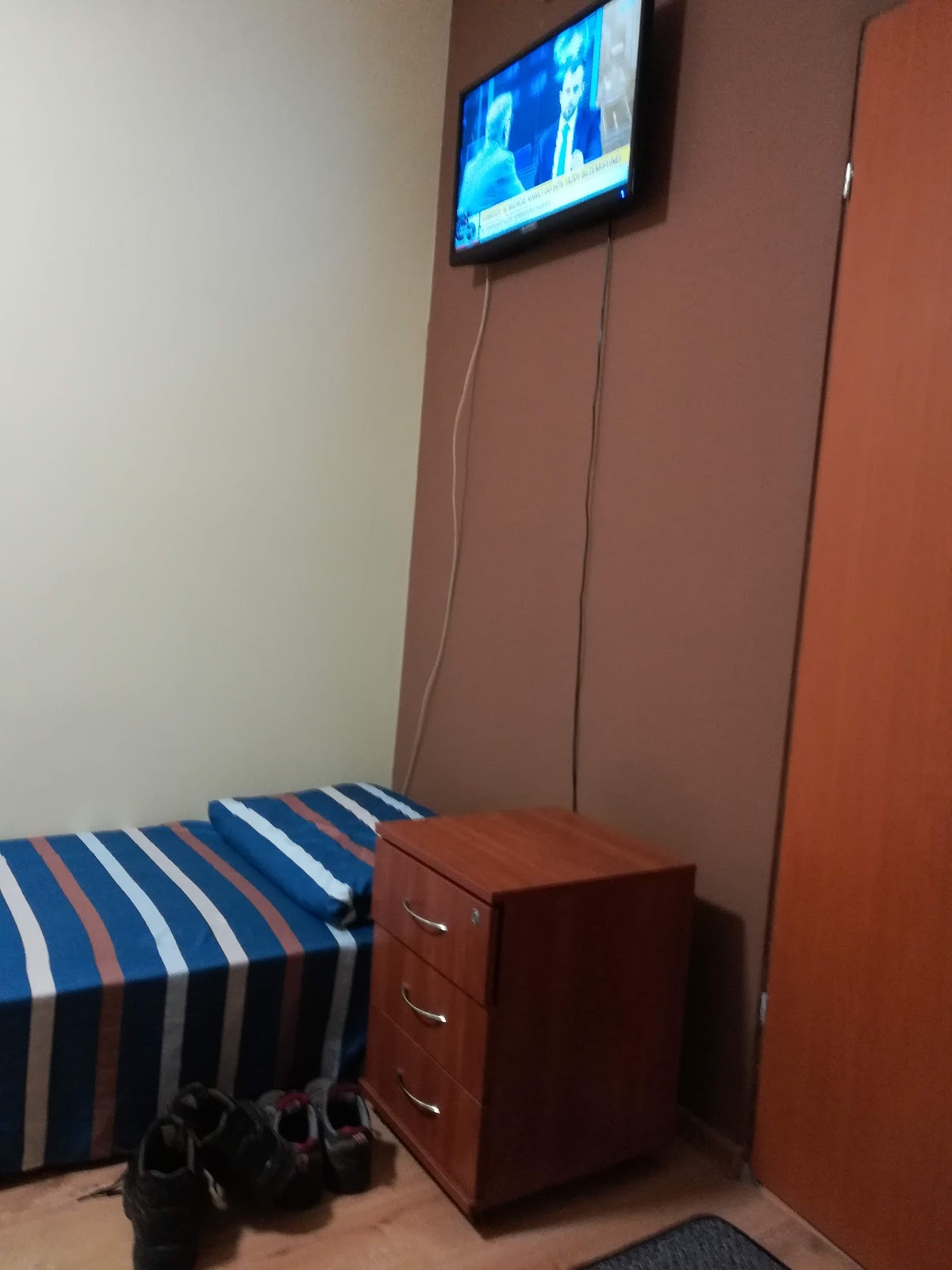 Łóżko pojedyncze, komoda i telewizor na ścianie